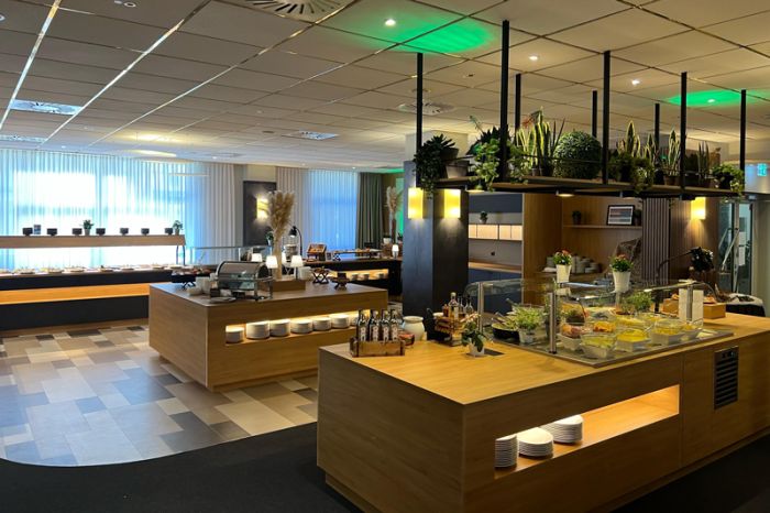 Restaurantbereich im NOVINA Hotel am Südwestpark Nürnberg mit mit Salatbuffet, Essensausgabe und Dessertbereich ohne Gäste und grüner Deckenbeleuchtung.