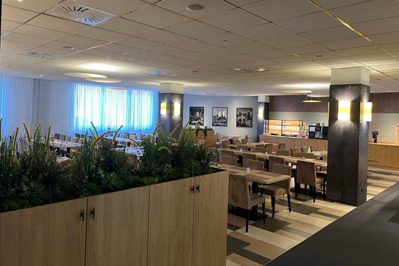 Dining room at the NOVINA Hotel at Südwestpark Nuremberg without guests, decorated with plants.