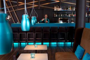View from the seating area of the bar and the bartender, as well as a variety of bottles at the Motel One Nuremberg-City hotel.