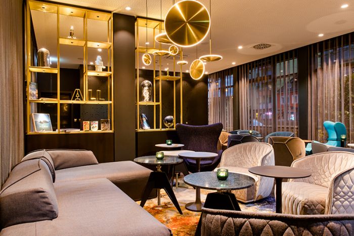 Lounge area with open shelving and lighting at Motel One Nuremberg-Plärrer.