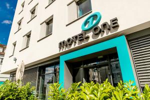 Oblique view of parts of the façade and entrance area with plants at the Motel One Nuremberg-Plärrer hotel.