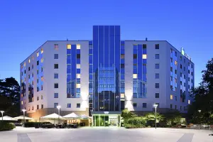 Novina Business Hotel at Südwestpark Nuremberg: Exterior view including main entrance, beer garden, and terrace at dusk.