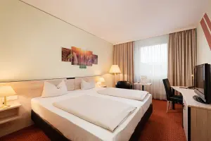 Novina Business Hotel at Südwestpark Nuremberg: Room view with double bed and TV, as well as window and curtain.