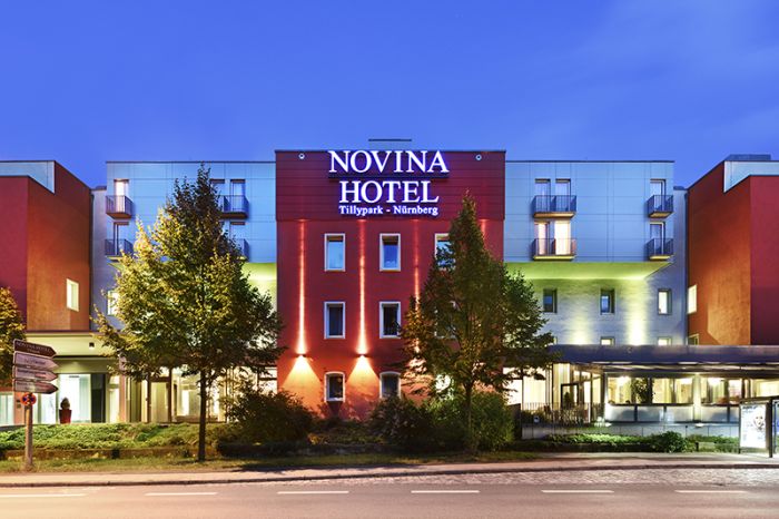 Novina Hotel Tillypark Nuremberg: Exterior view with illuminated main entrance at dusk from across the street.