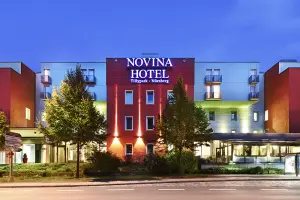 Novina Hotel Tillypark Nuremberg: Exterior view with illuminated main entrance at dusk from across the street.