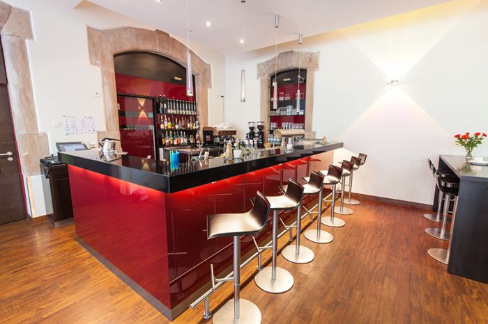 Novina Hotel Tillypark Nuremberg: View of bar with red paneling and black shelf, including bar stools, without guests.