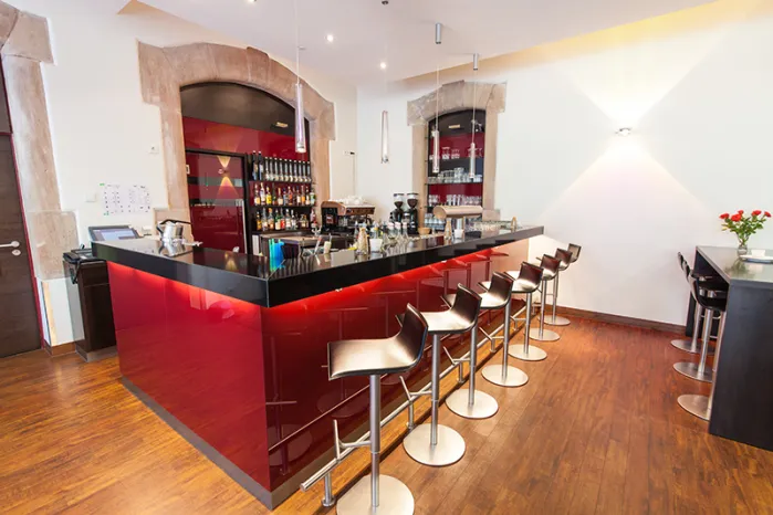 Novina Hotel Tillypark Nuremberg: View of bar with red paneling and black shelf, including bar stools, without guests.