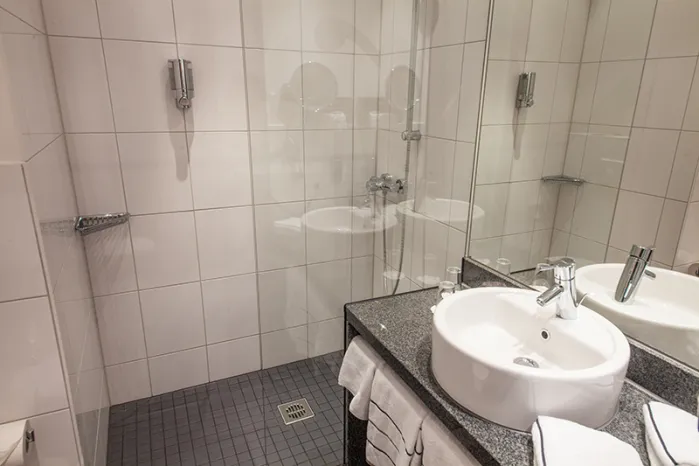 Novina Hotel Tillypark Nuremberg: View of standard bathroom with white tiles, glass shower, and sink
