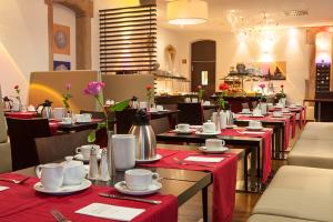 Novina Hotel Tillypark Nuremberg: View of the breakfast area with tables set with flowers, tableware, coffee pots, and red tablecloths.