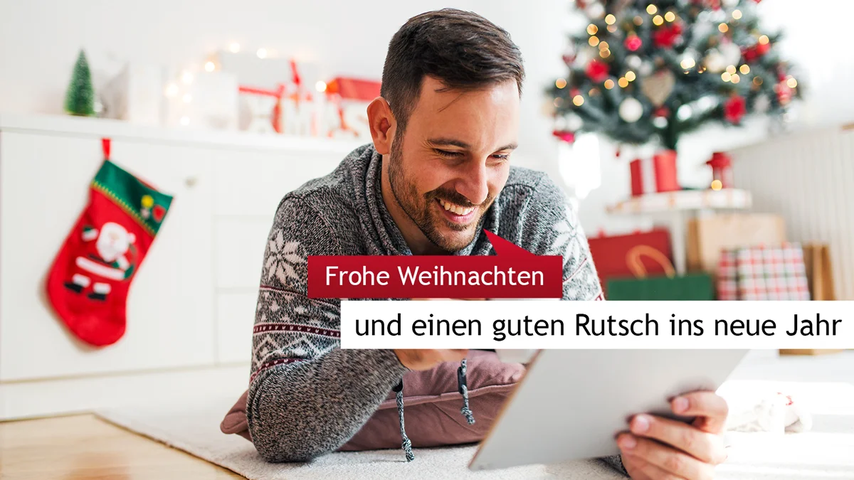 Mann mit Tablet in weihnachtlich dekoriertem Wohnzimmer